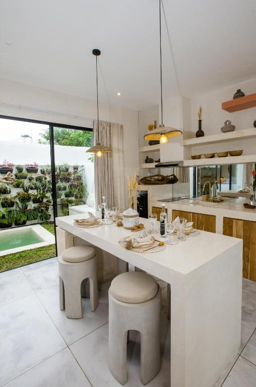 a kitchen with a large white island with stools at Bali Escapes- Studio And 1 Bedroom Villa in Uluwatu
