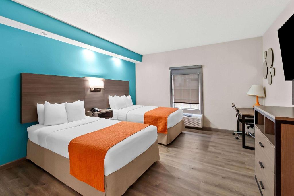a hotel room with two beds and a desk at Howard Johnson by Wyndham Jackson in Jackson