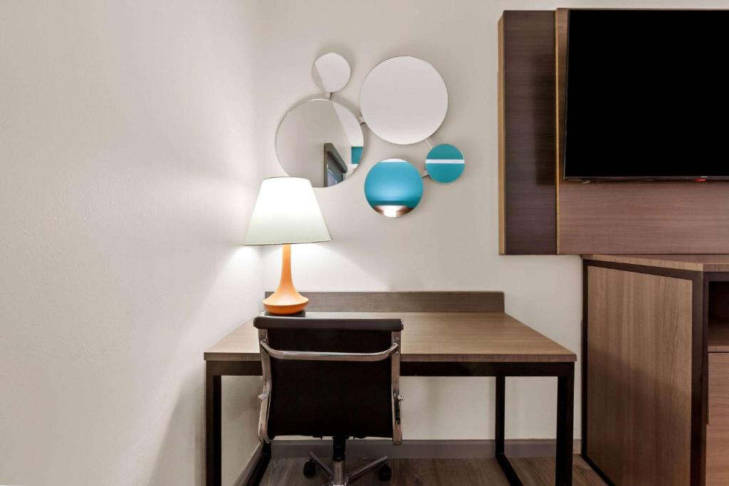 a room with a desk with a lamp and a tv at Howard Johnson by Wyndham Jackson in Jackson