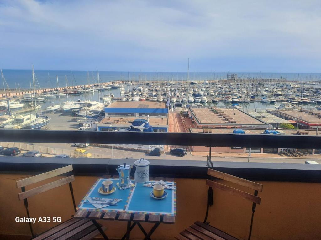 balcone con tavolo e vista su un porto turistico. di La Suite Sinatra a Nettuno