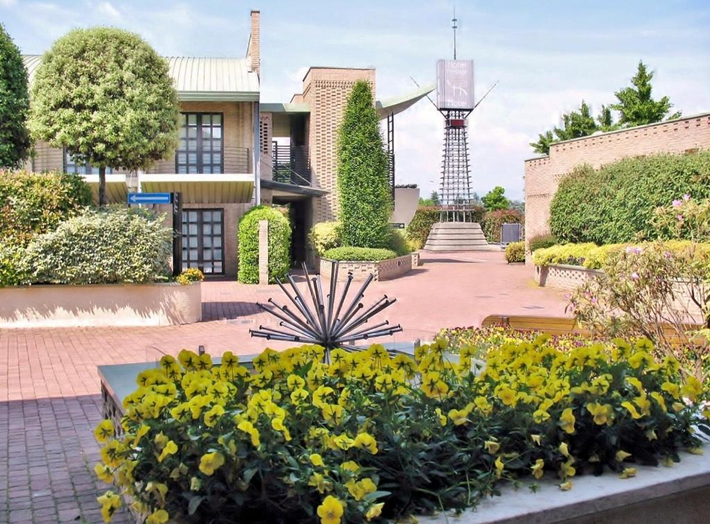 un giardino con fiori gialli di fronte a una casa di B&B Hotels HOTEL PRESTIGE ORNAGO a Ornago