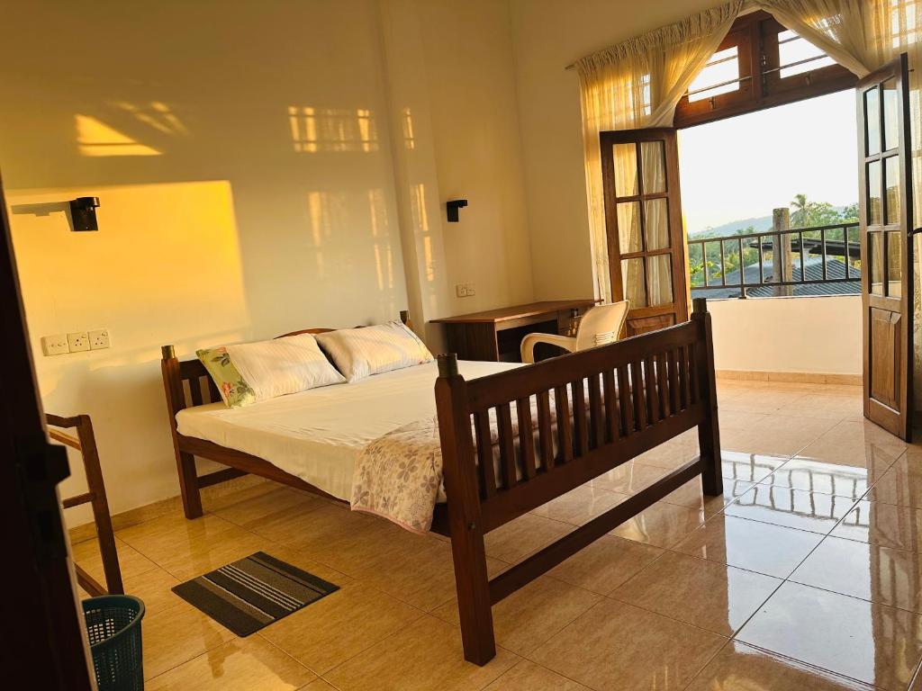 a bedroom with a bed and a desk and a balcony at Skyline Stay Guest House in Galle