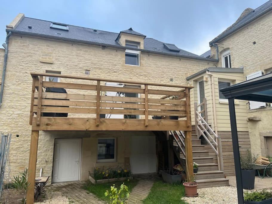 une maison avec une terrasse en bois devant elle dans l'établissement Maison à Luc sur Mer, à Luc-sur-Mer