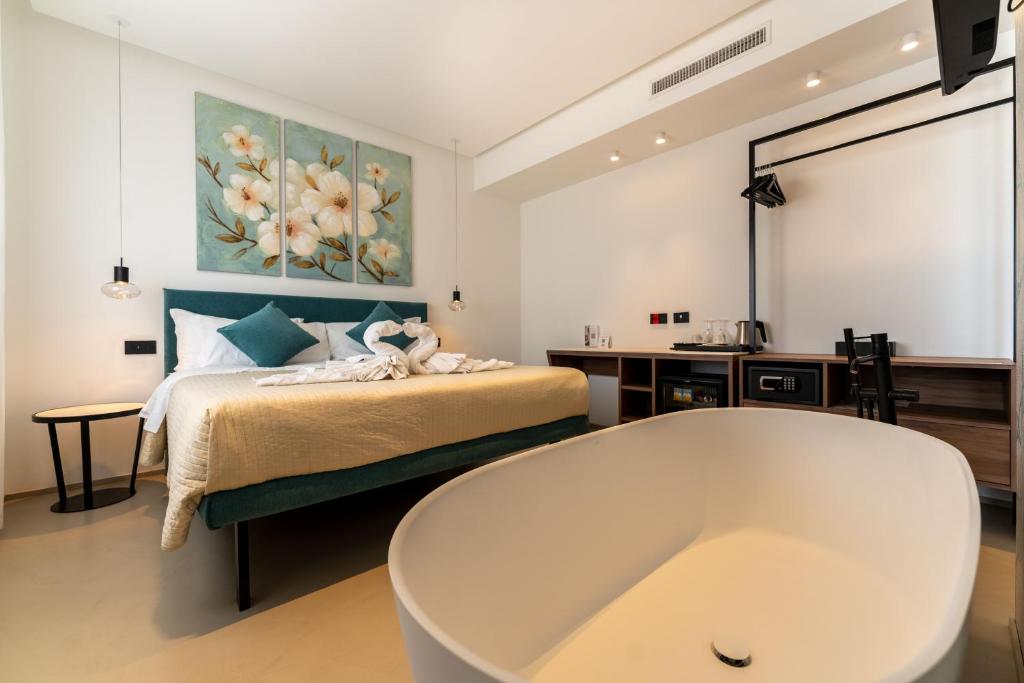 Baño con bañera junto a una cama con pintura en B&amp;B Le Suites di Costanza, en Cefalú