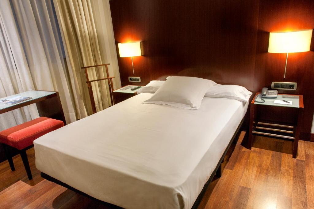 a bedroom with a large white bed and a desk at Zenit Valencia in Valencia