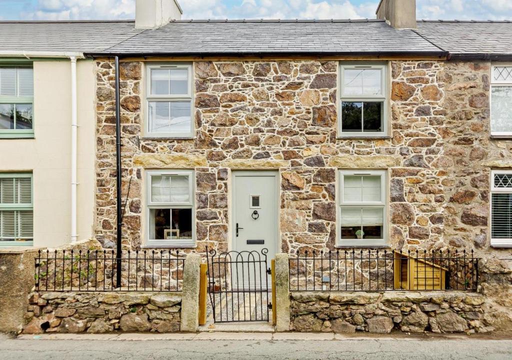 an old stone house with a white door at Ty Fin Cottage with Hot Tub in Llanbedrog
