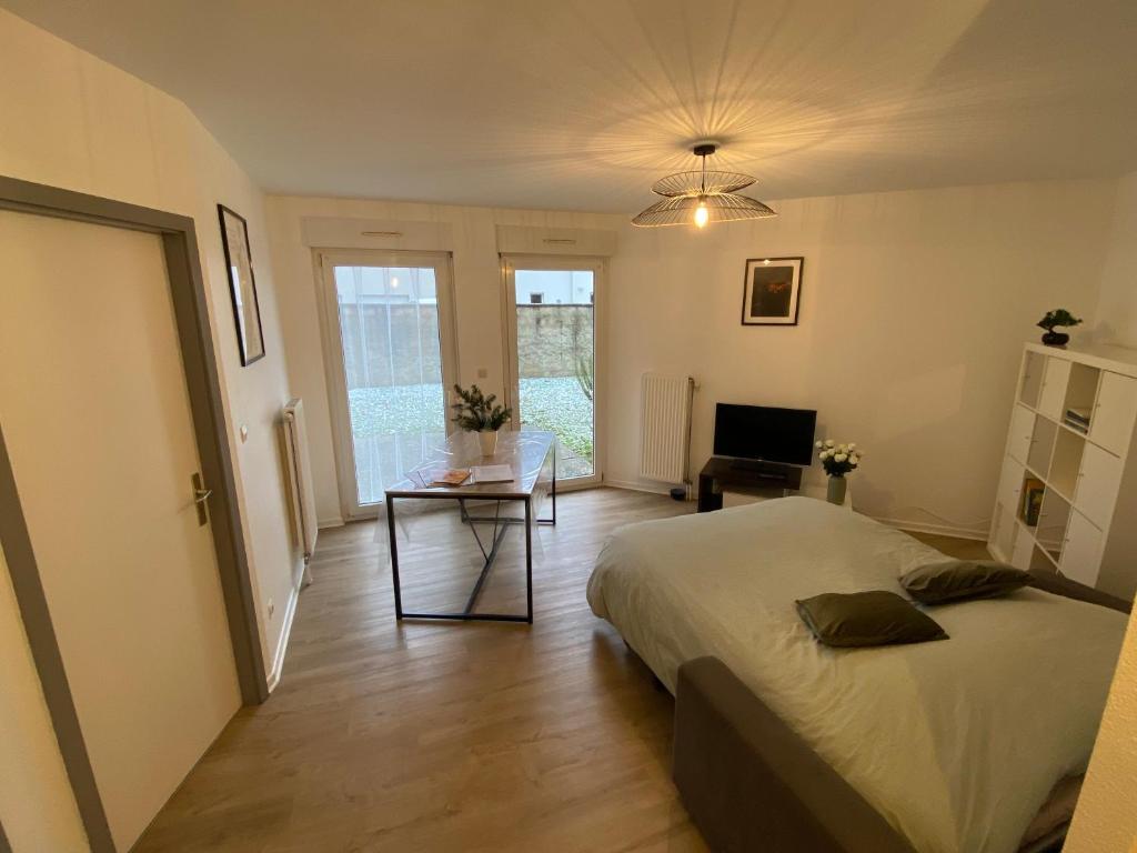 une chambre avec un lit, une table et une télévision dans l'établissement Cocon au cœur de l'Alsace, à Horbourg-Wihr