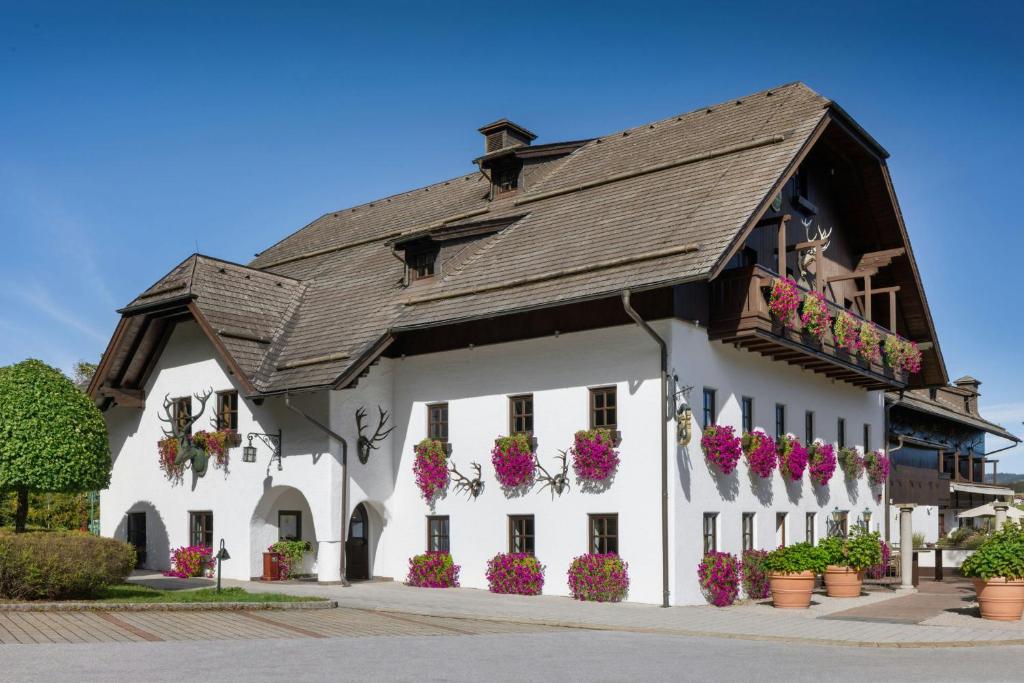 a white building with flowers on the side of it at Arabella Jagdhof Resort am Fuschlsee, a Tribute Portfolio Hotel in Hof bei Salzburg