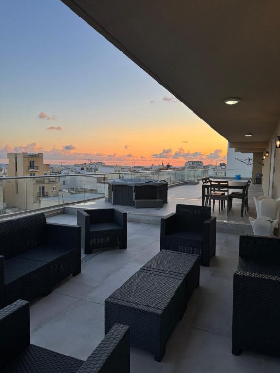 un patio all'ultimo piano con divani e tavolo con tramonto di Skyline Soak, Views & Jacuzzi a San Giuliano