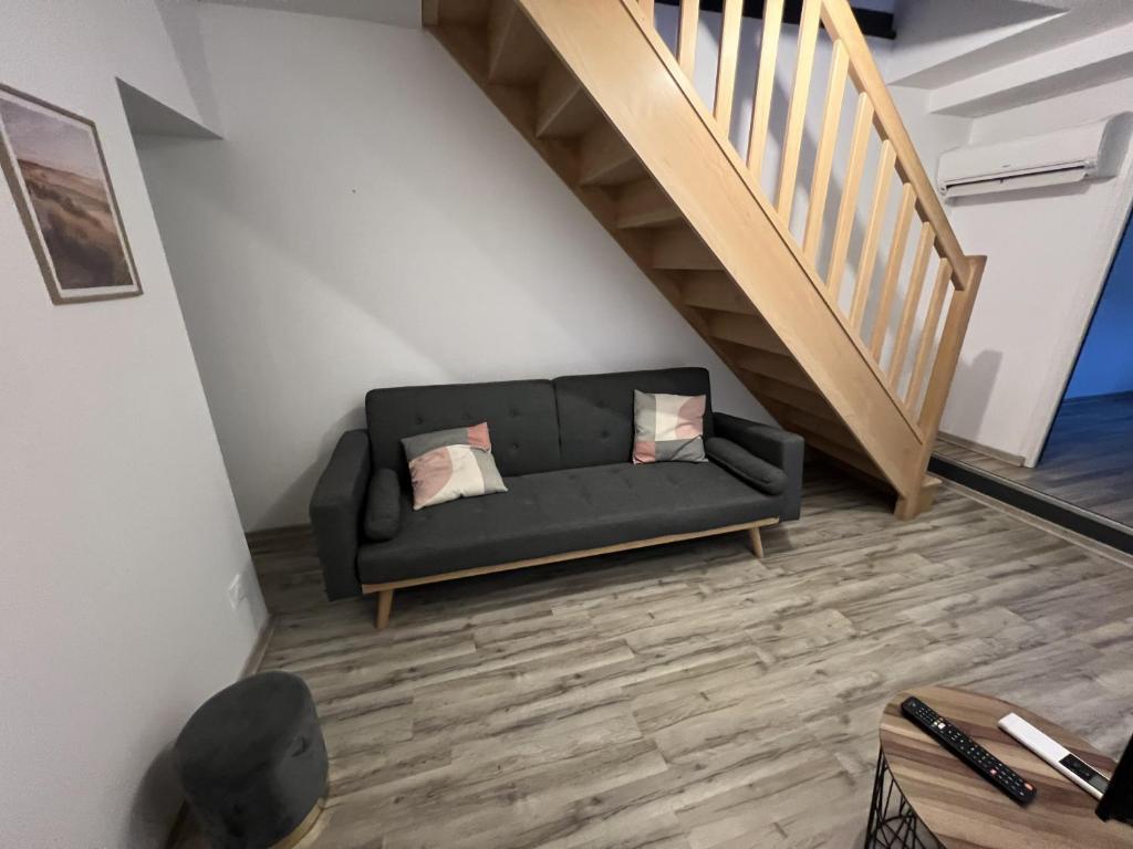 - un canapé noir dans une pièce avec un escalier dans l'établissement Cote Jardin, AMIENS 4-6 P, à Amiens
