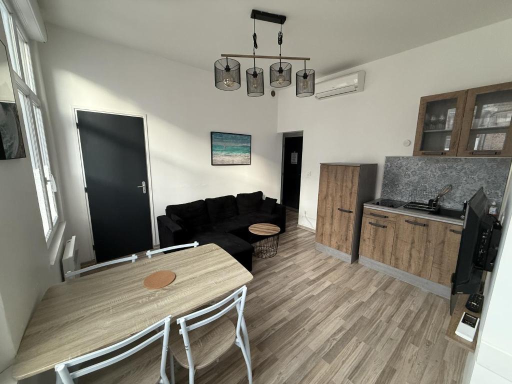 un salon avec un canapé noir et une table dans l'établissement Amiens, appart douillet 2-4P, à Amiens