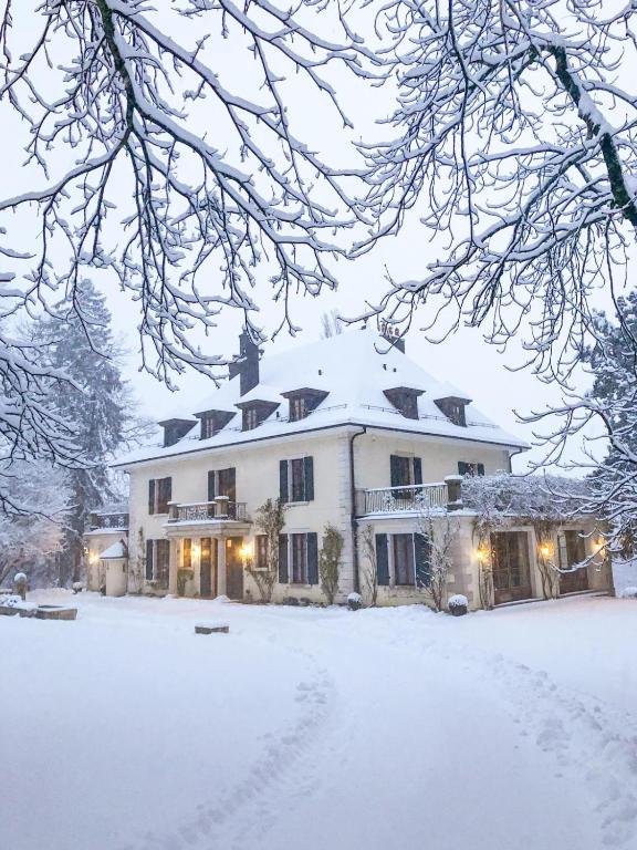 Une grande maison blanche recouverte de neige dans l'établissement Chateau d 'Echenevex, Geneva, à Échenevex