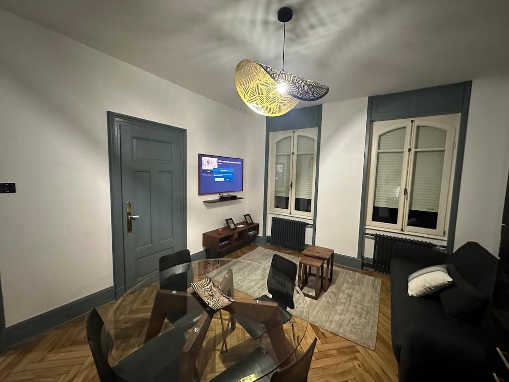 a living room with a glass table and a tv at Appartement dans Maison de Maître in Schiltigheim