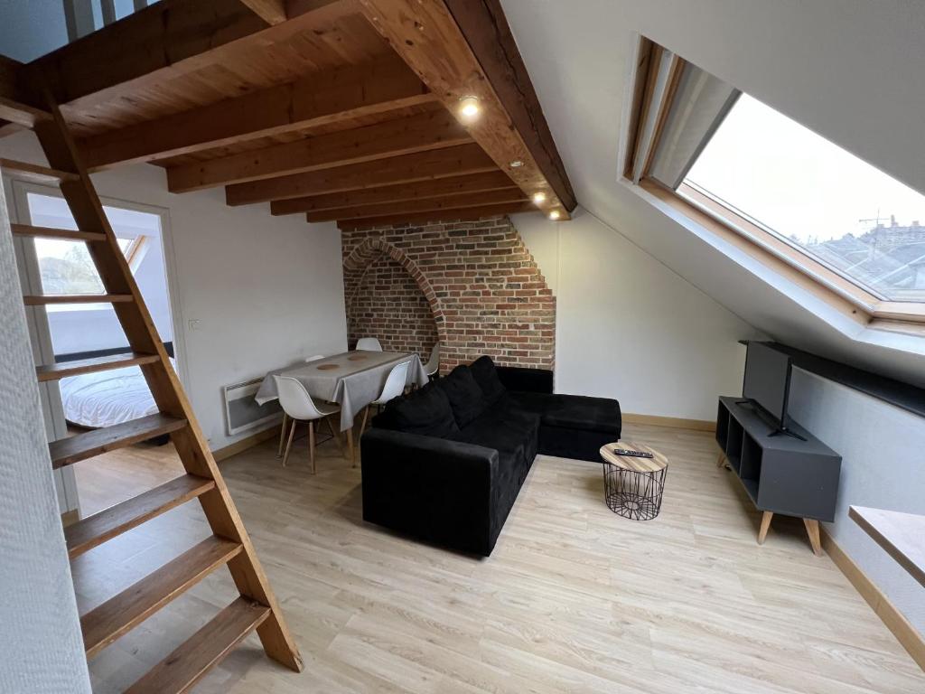 un salon avec un canapé noir et une table dans l'établissement Amiens, sous les toits 4-6 pers, à Amiens