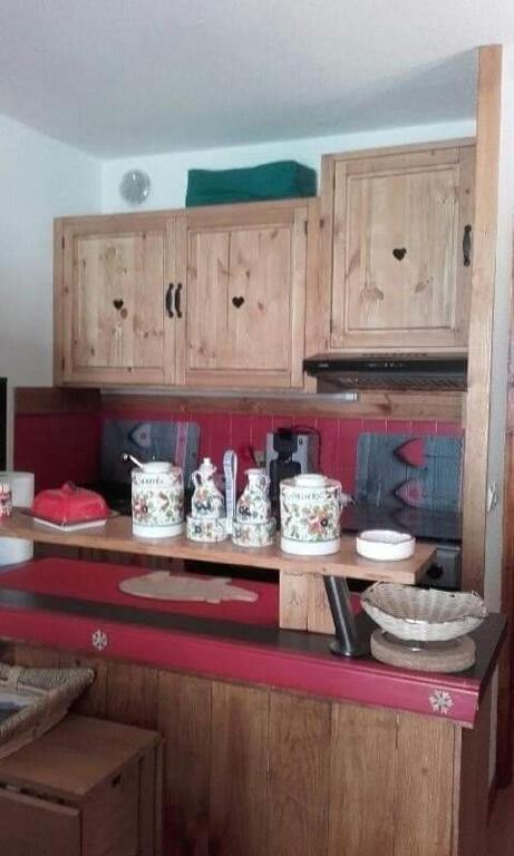 une cuisine avec des placards en bois et un comptoir rouge dans l'établissement Chalet des loulous, à Narreyroux
