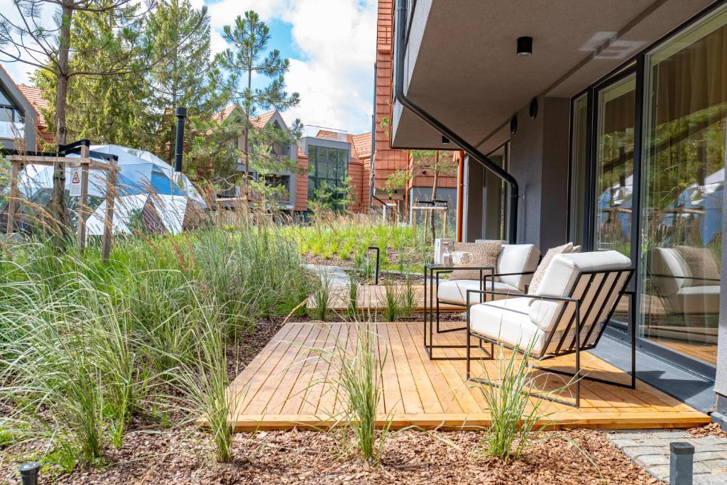 een patio met 2 stoelen en een tafel in de tuin bij Hill Apartment in Palanga
