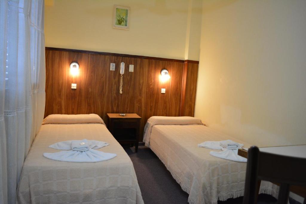 a hotel room with two beds with white sheets at Gran Hotel Amelia in Mar del Plata