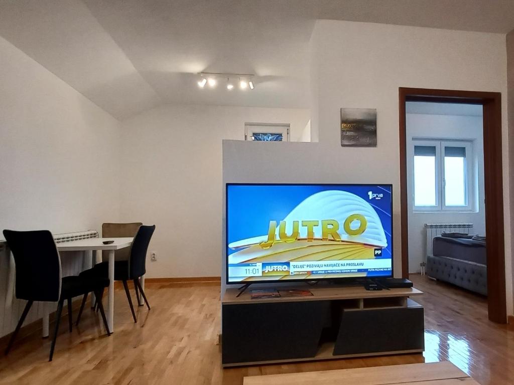 a living room with a tv and a table with chairs at Apartman EXPO Surčin in Surčin