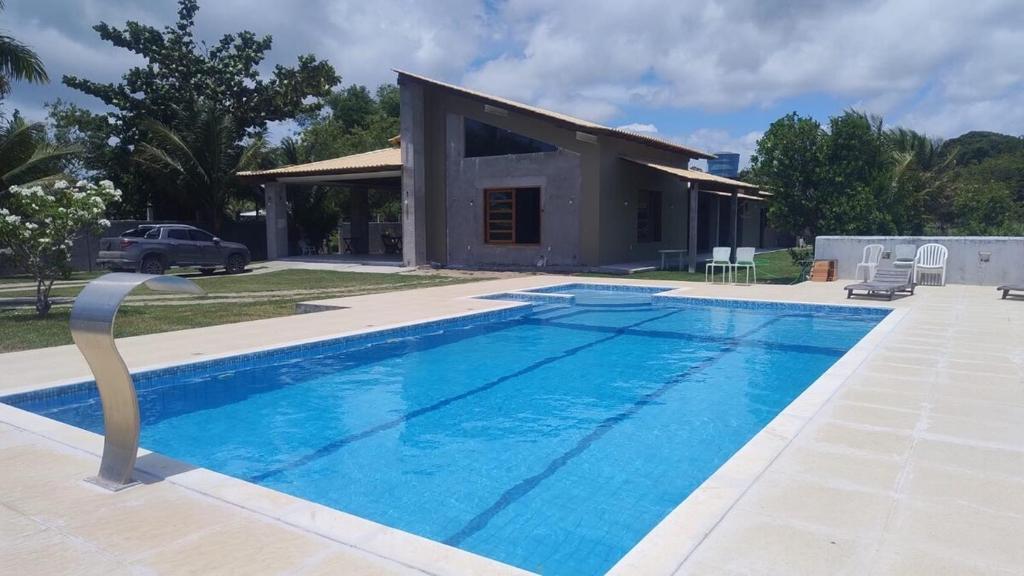 a swimming pool in front of a house at Sítio Recanto dos pássaros in Porto Seguro