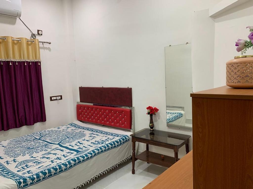 a bedroom with a bed and a table and a mirror at Kolkata Sarkar Villa Homestay in Kolkata