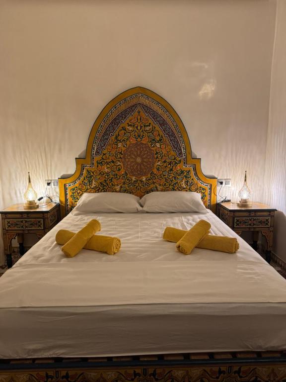 a large bed with two yellow pillows on it at Appartement Dar LALA 2 in Fez