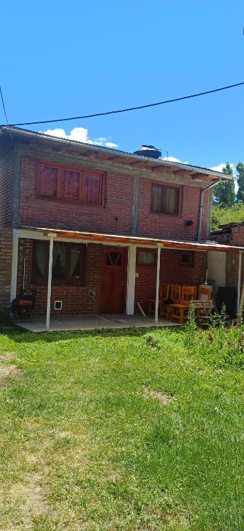 a red brick house with a lawn in front of it at Alojamiento Rivadavia in El Bolsón