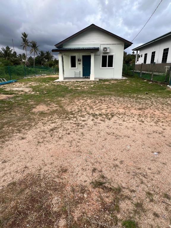 a white house with a large yard in front of it at Teratak Manis Homestay in Kuantan