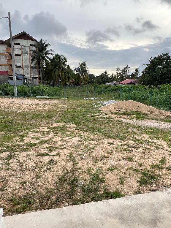 a field of grass with a building in the background at Teratak Manis Homestay in Kuantan