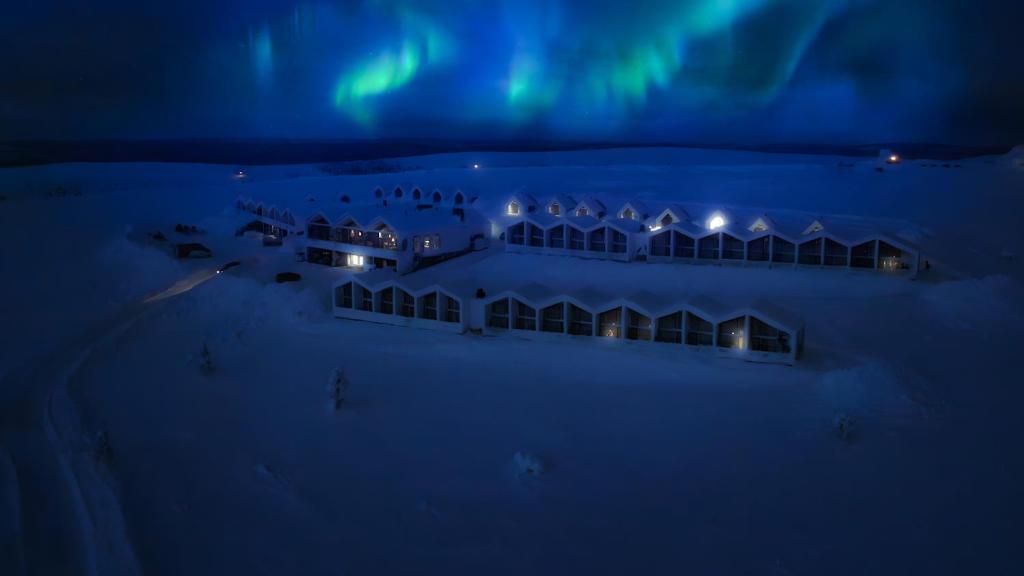 une vue aérienne d'un hôtel sous les aurores boréales la nuit dans l'établissement Star Arctic Hotel & Activities, à Saariselka