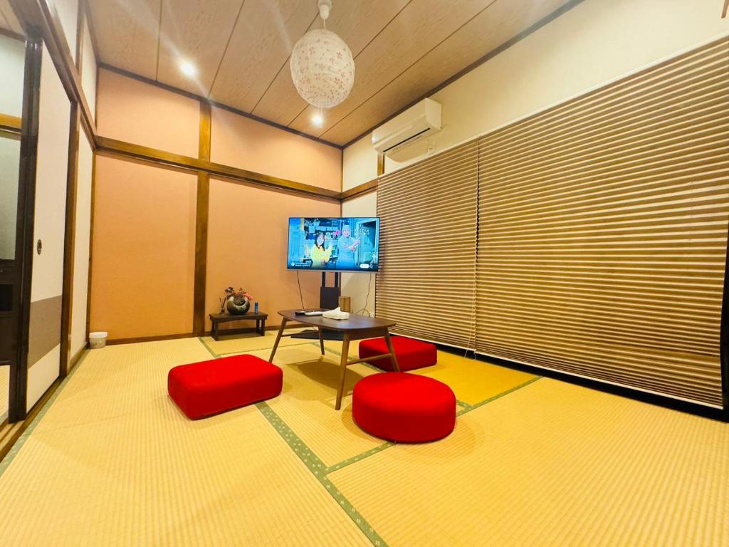 una camera con sedie rosse, tavolo e TV di Oji House-KI0022 a Tokyo