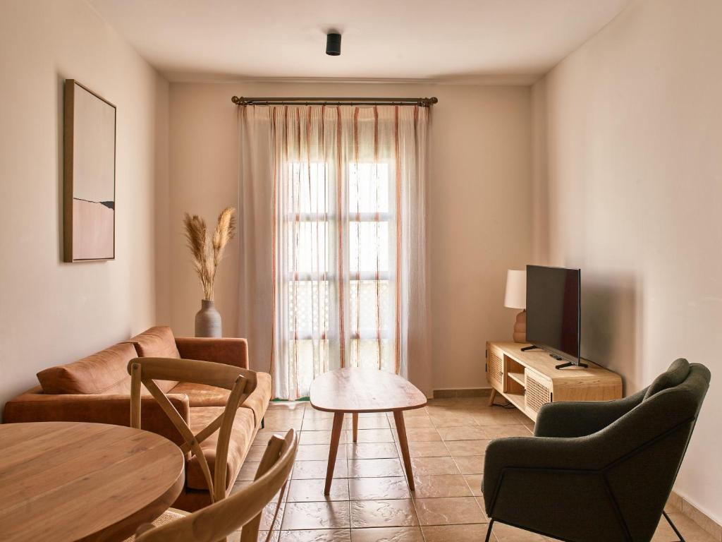 a living room with a couch and a tv and a table at Apartamentos Turísticos Casa de La Borrega in Estepona