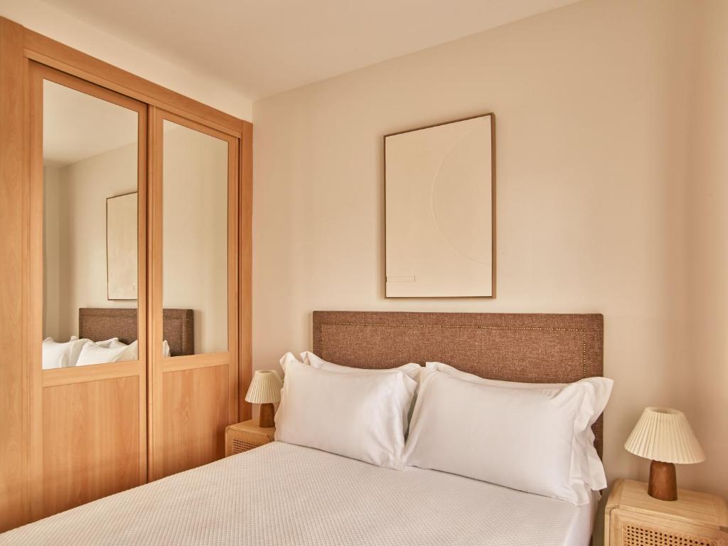 a bedroom with a bed with white pillows and a mirror at Apartamentos Turísticos Casa de La Borrega in Estepona