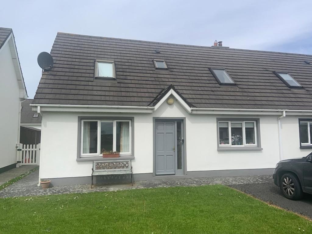 a white house with a black roof at Fionas Seaside Cottage in Ballybunion