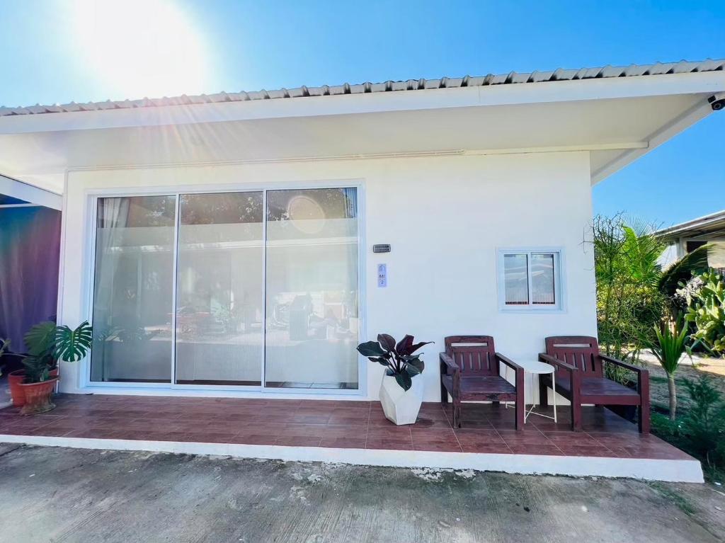a white house with two chairs and a patio at Sandy house Pai 2 in Pai