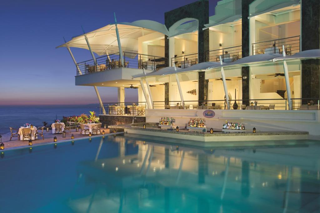 a large building with a swimming pool next to the ocean at Secrets Vallarta Bay Resort & SPA - Adults Only in Puerto Vallarta