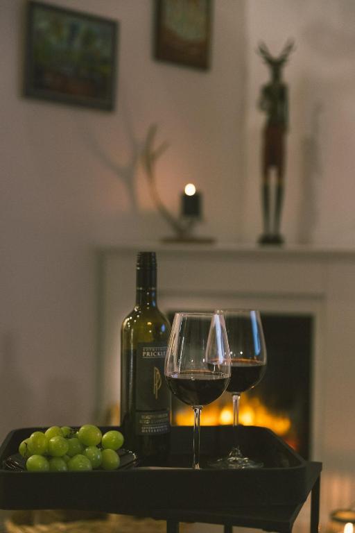two glasses of wine next to a bottle of wine and grapes at "Hunter's Suite"- at the heart of Hartberg I Parking in Hartberg