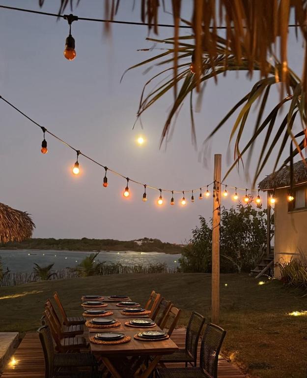a long wooden table with chairs and lights at Tatadise in Tatajuba