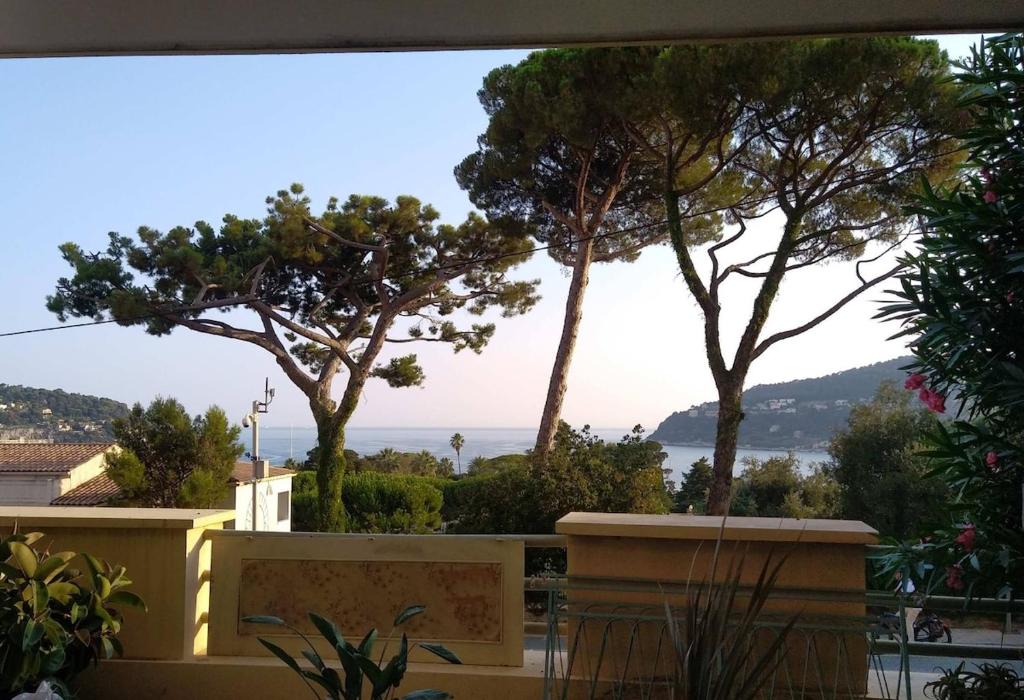 une vue sur l'océan depuis un balcon avec des arbres dans l'établissement Loft avec vue sur la Rade, à Villefranche-sur-Mer