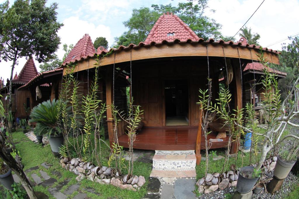 uma pequena casa de madeira com um telhado vermelho em Omah Garengpoeng Guest House em Borobudur