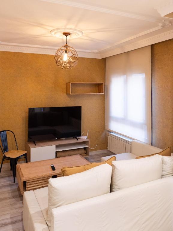 a living room with white furniture and a flat screen tv at Apartamento Los Castillos 1I in Tordesillas