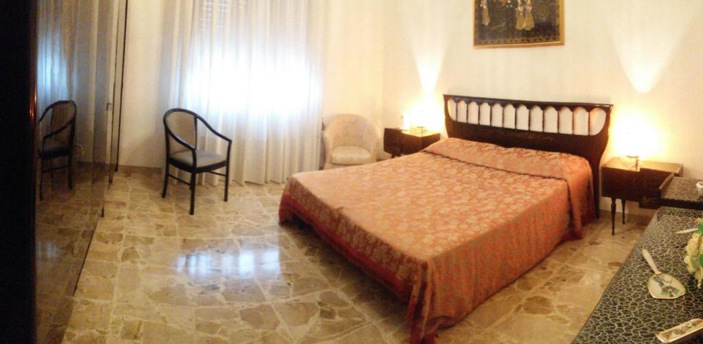 een slaapkamer met een bed en stoelen in een kamer bij Apartment Nonna Cucca in Cecina