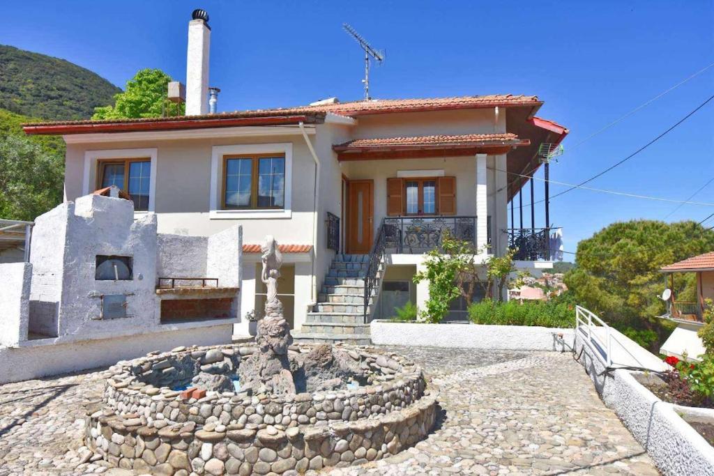 a house with a fountain in front of it at KarolinaHouse in Ágios Matthaíos