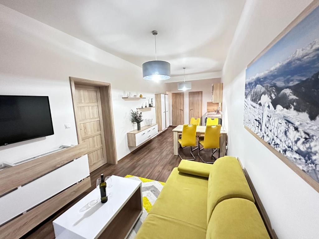 a living room with a yellow couch and a tv at Apartmán Orech in Belá