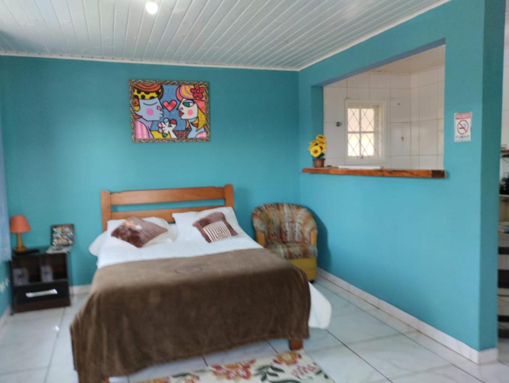 a blue bedroom with a bed and a window at Pousada Cantinho da Mi & Teco in Campos do Jordão