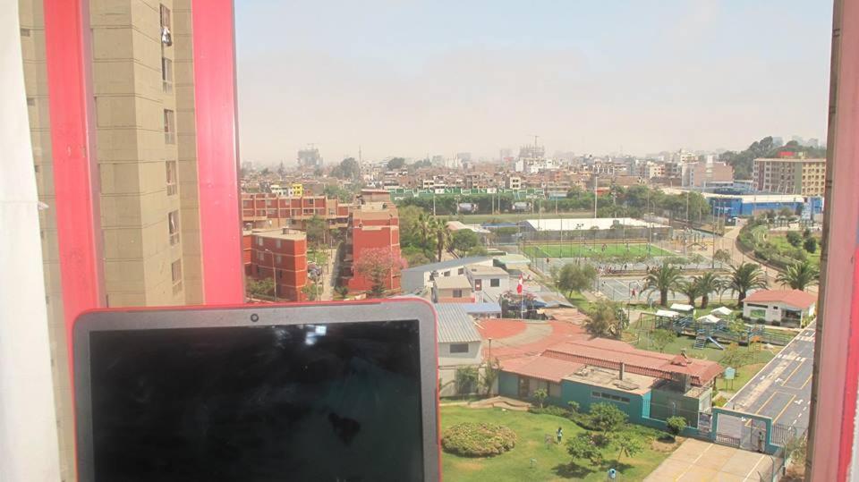 a computer monitor sitting on a window with a view of a city at Cozy Room - Margot Arimborgo in Lima