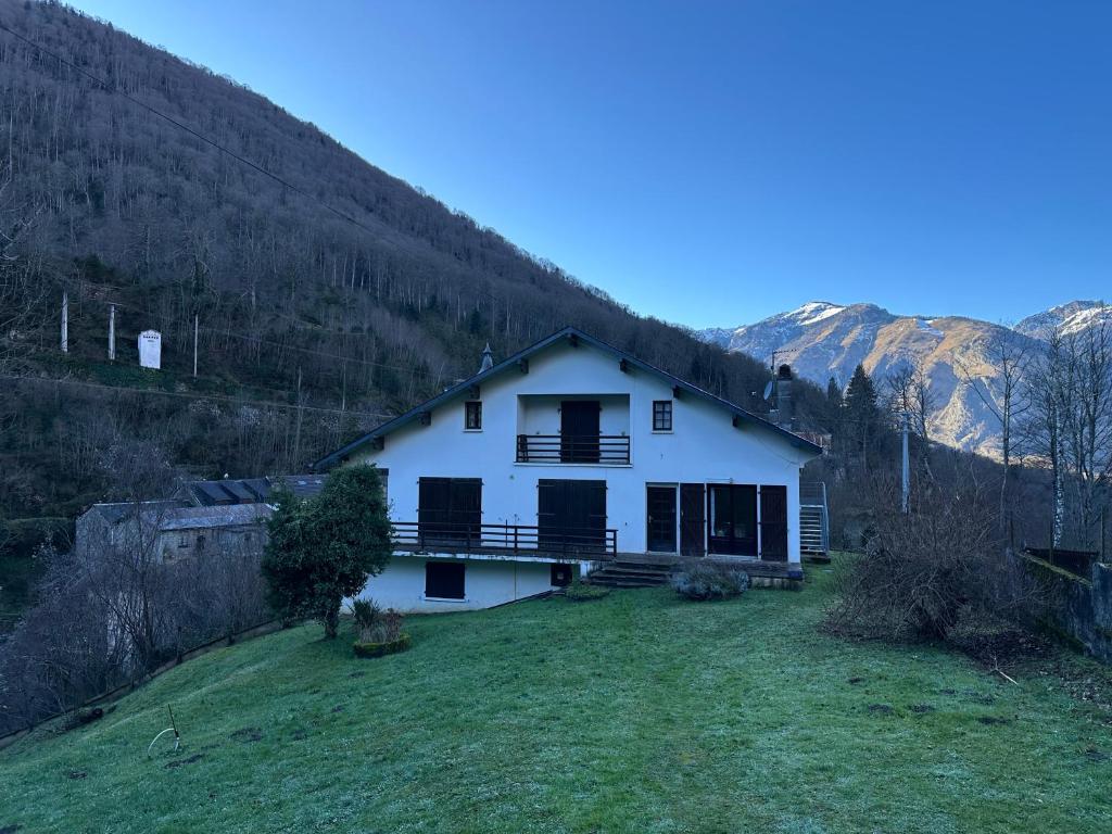 une maison blanche sur une colline avec des montagnes en arrière-plan dans l'établissement Chalet ARTIGALAS, à Eaux-Bonnes
