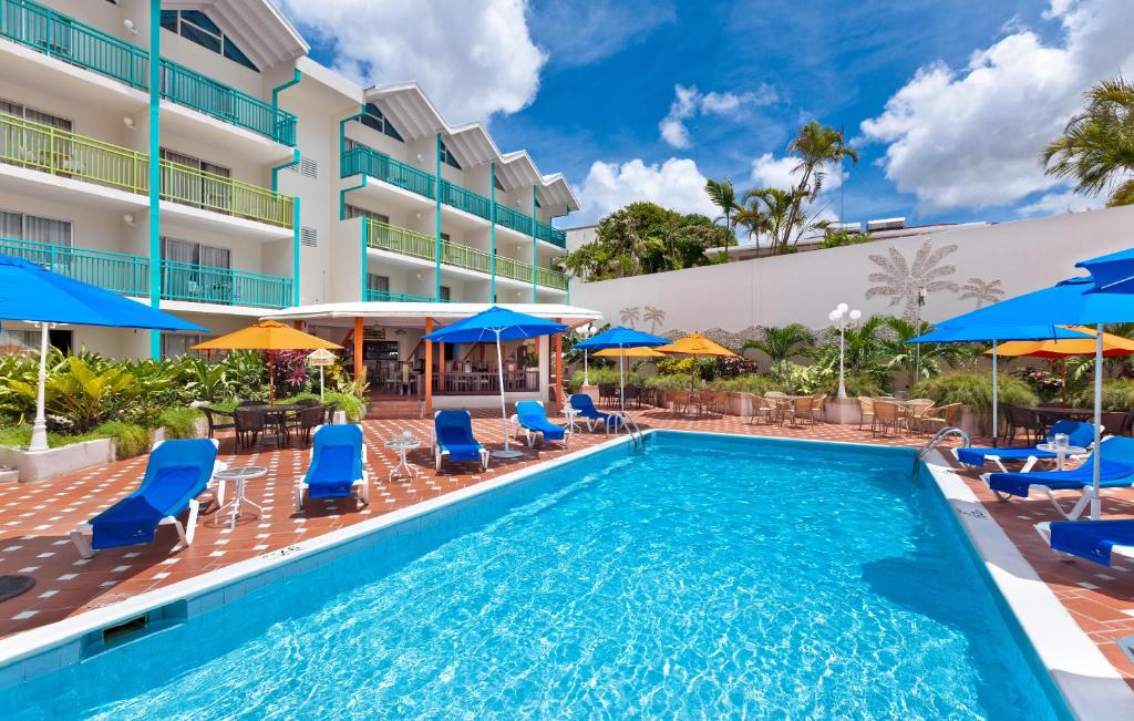 a swimming pool with blue chairs and blue umbrellas at Blue Horizon Hotel in Bridgetown