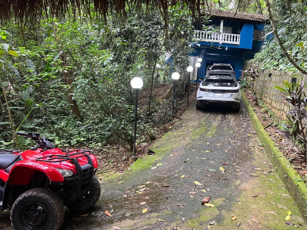 un ATV rojo estacionado en un camino de tierra junto a un coche en Casa Condomínio Praia Félix, en Ubatuba
