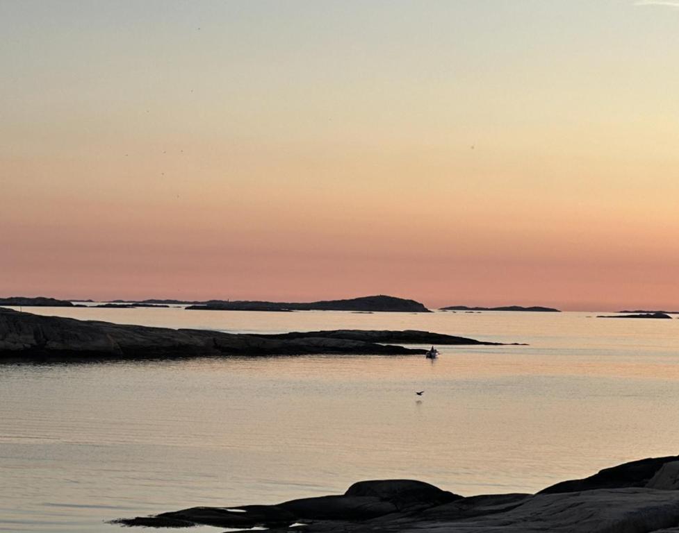 a sunset over a body of water with rocks at Atelier Blå houses in Rösselvik