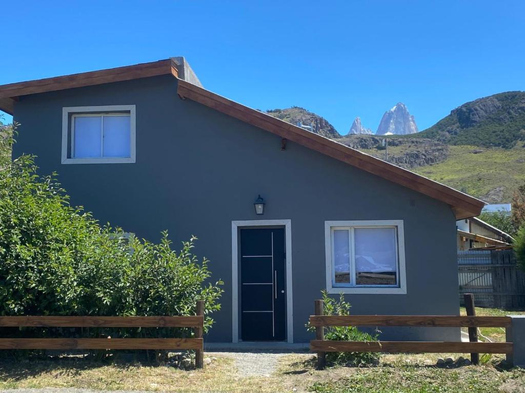 a blue house with mountains in the background at Casa Los Huemules in El Chalten